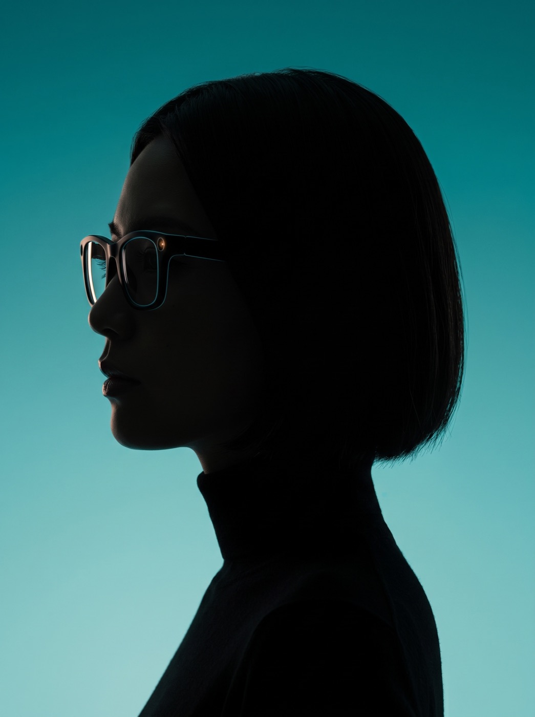 A young Japanese woman in profile, wearing Glimpse Glasses, as a dark silhouette on teal