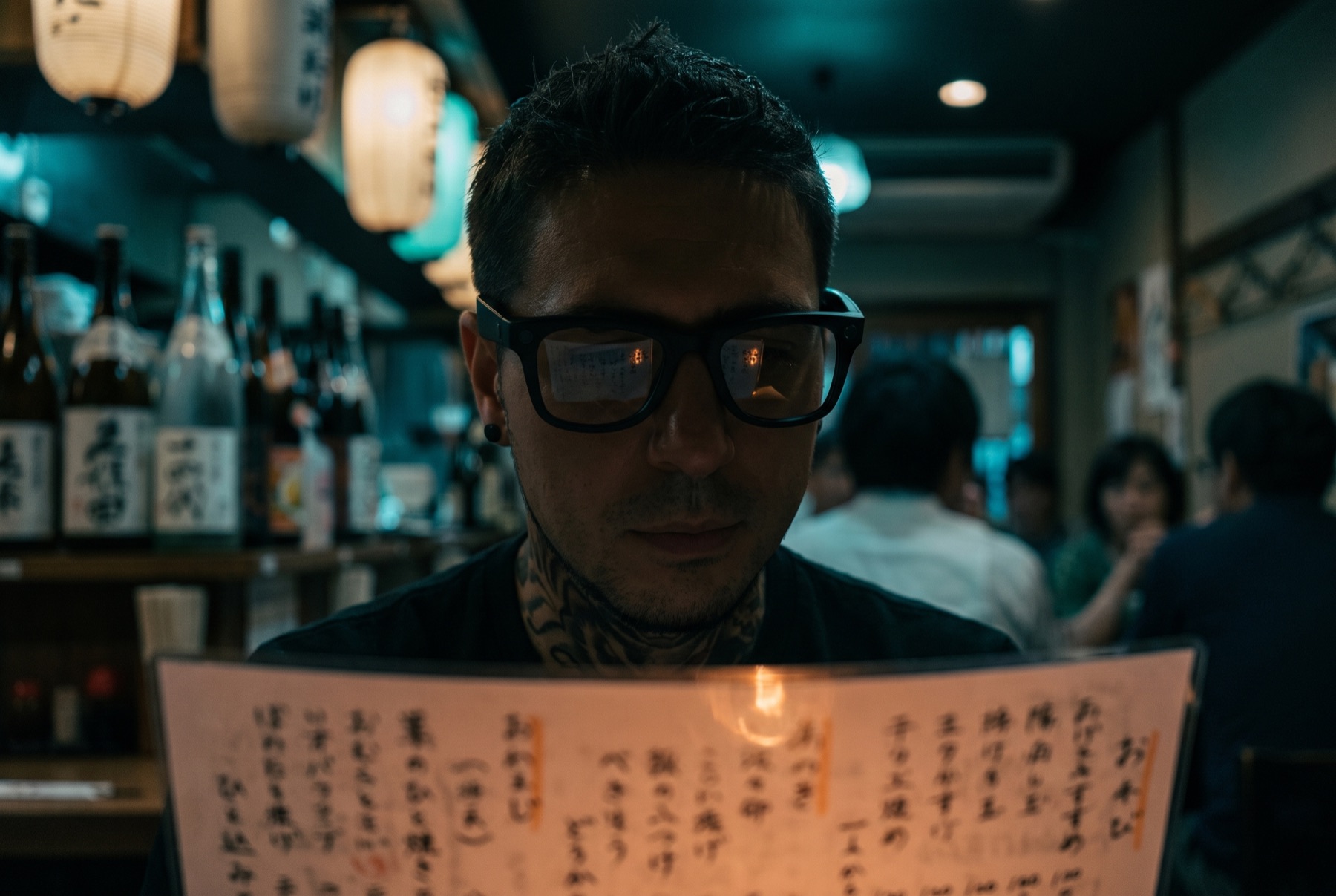 A man wearing Glimpse Glasses reads a handwritten menu in a small Japanese restaurant